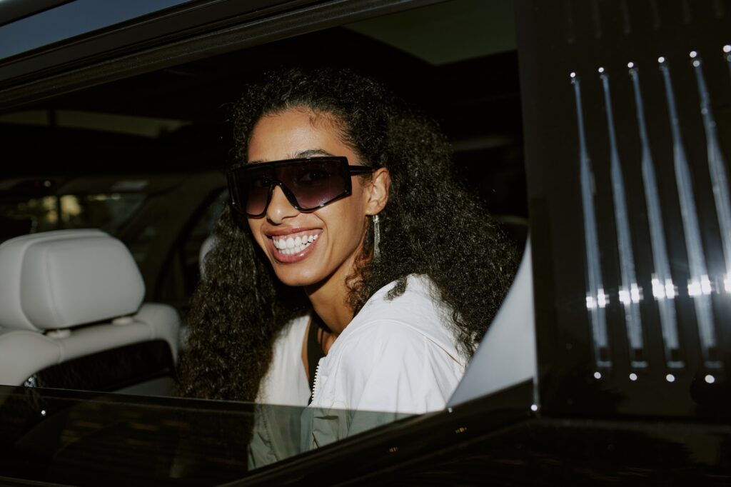 Portrait of Smiling Female Celebrity in Sunglasses Sitting in Car